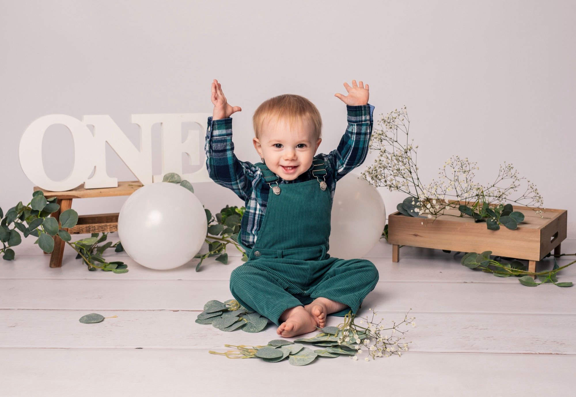 Petit garçon debout parmi des ballons verts et blancs pour son premier anniversaire (4)