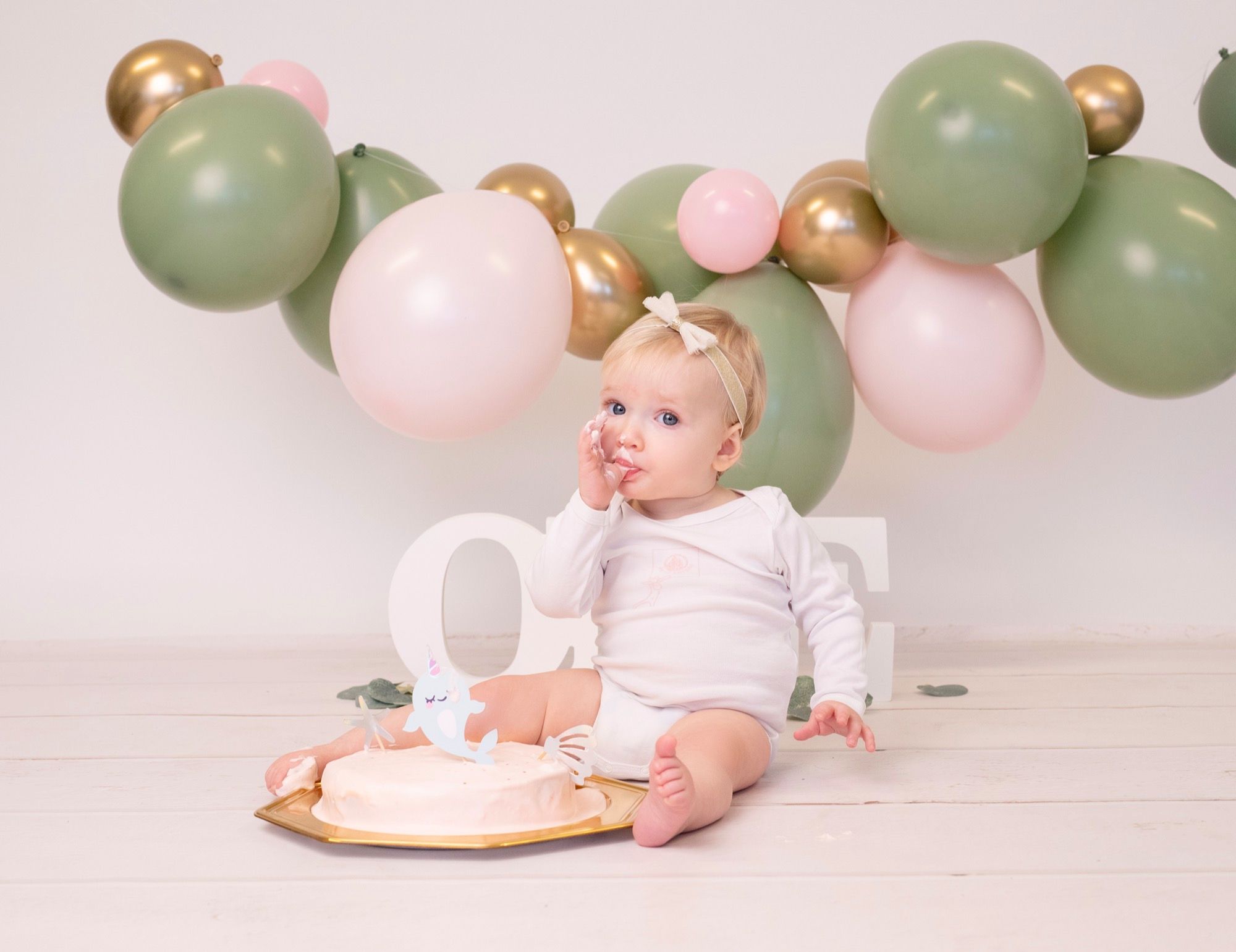 Petit garçon debout parmi des ballons verts et blancs pour son premier anniversaire (10)