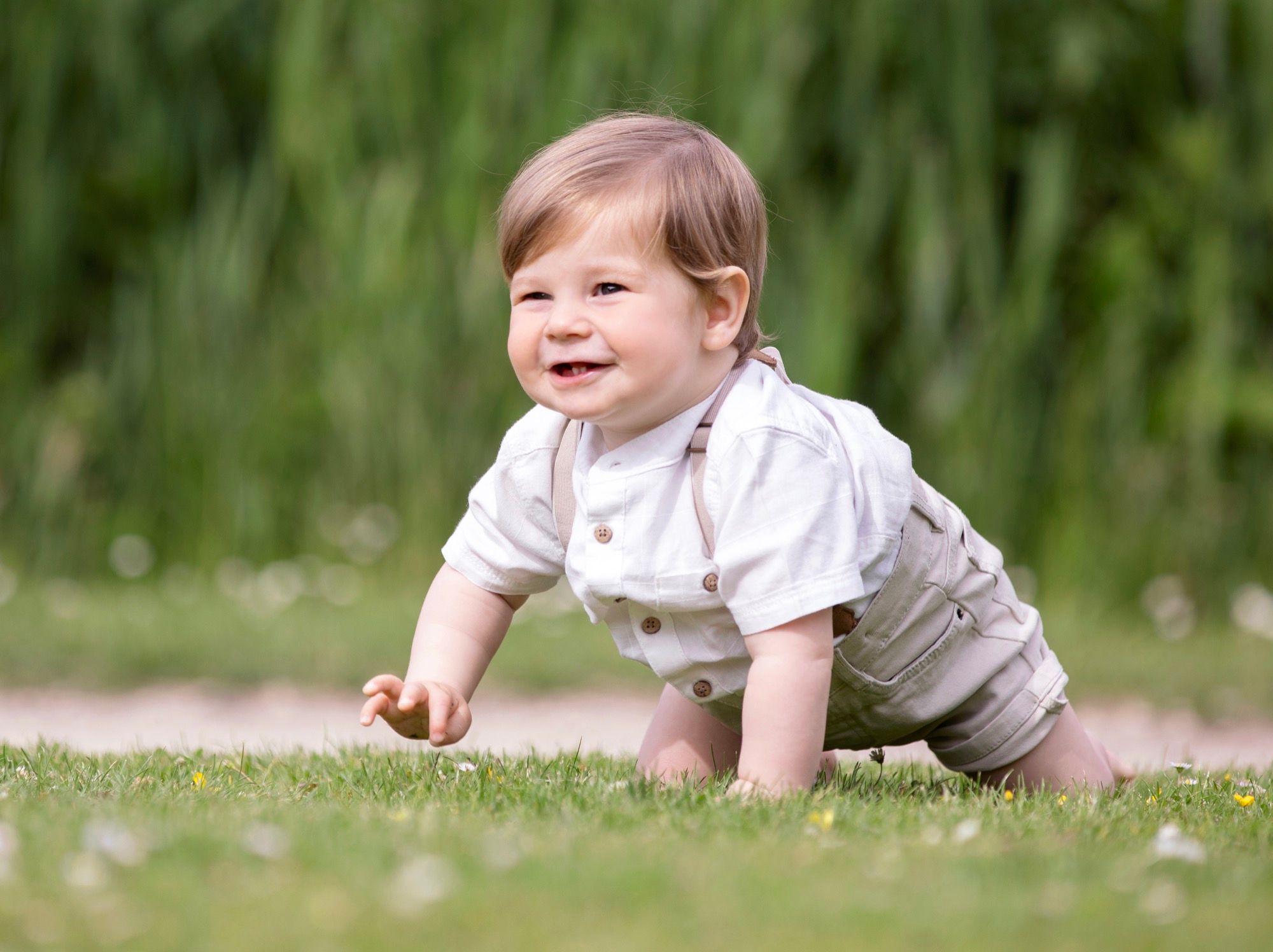 Smiling baby crawling in the grass, outdoor baby photo session