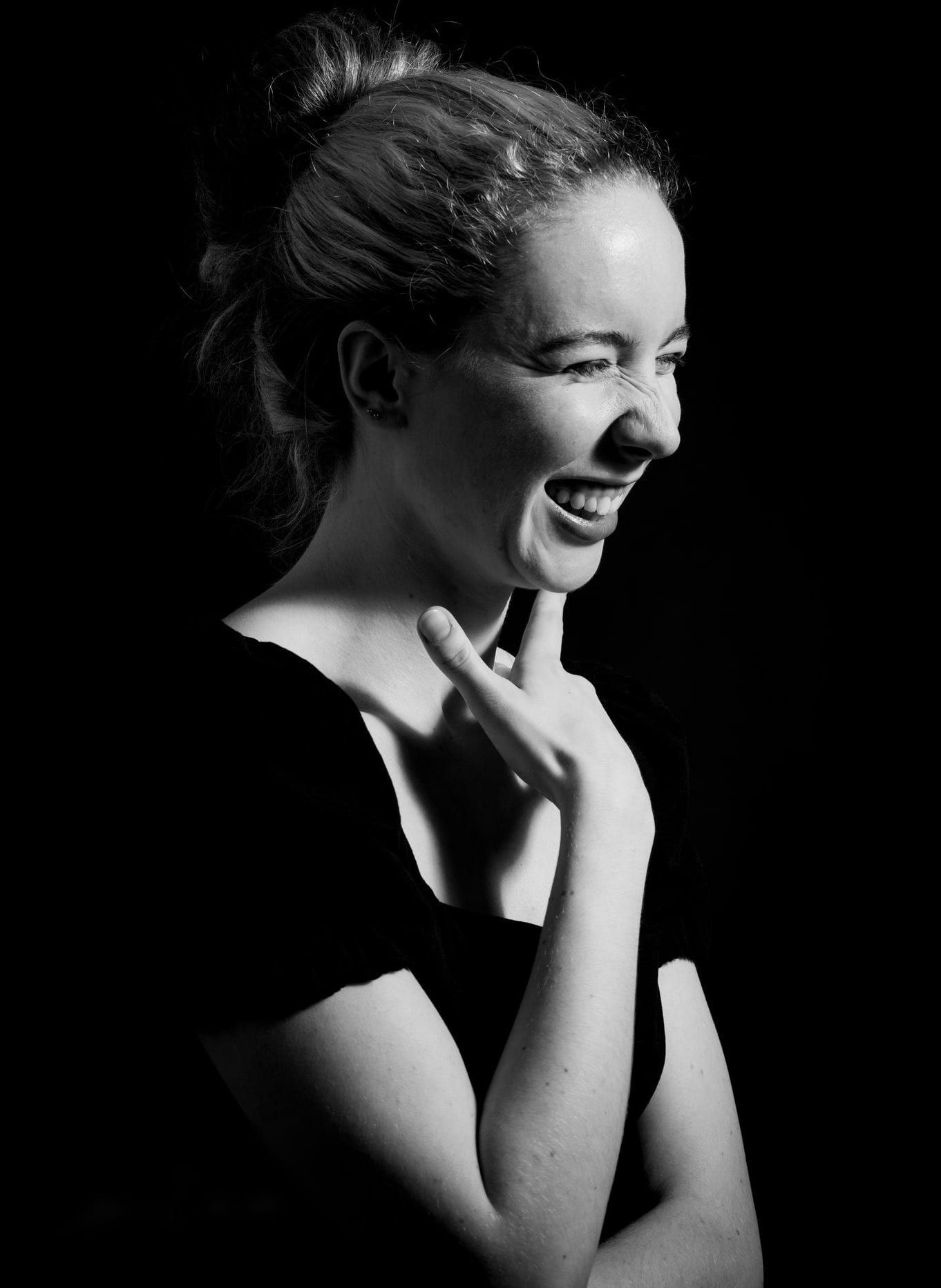 Femme riant aux éclats sur fond noir, portrait en noir et blanc en studio