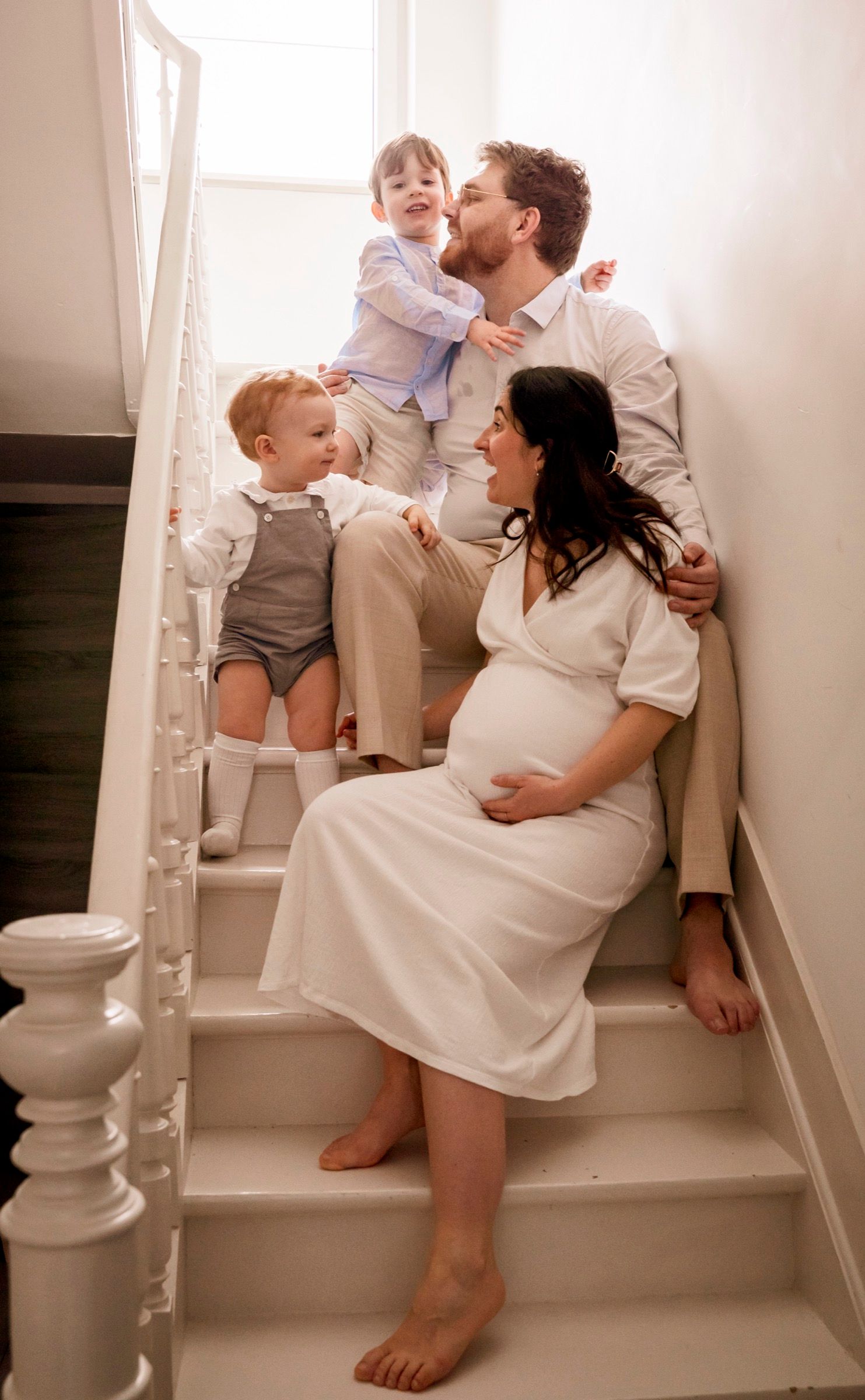 Family sitting on a staircase at home, parents and two children
