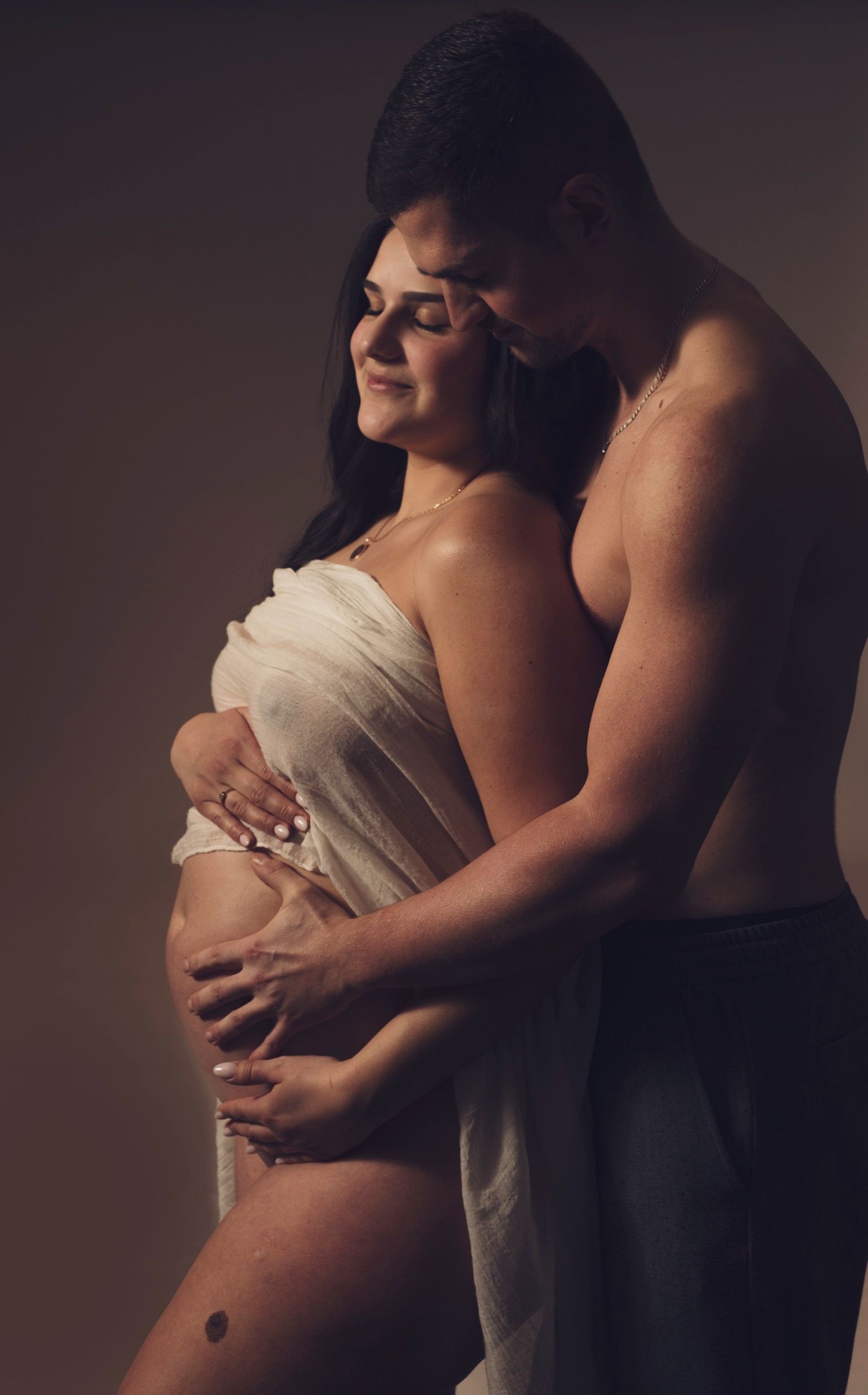 Couple expecting a child, hands together on the bump, maternity photo session as a couple