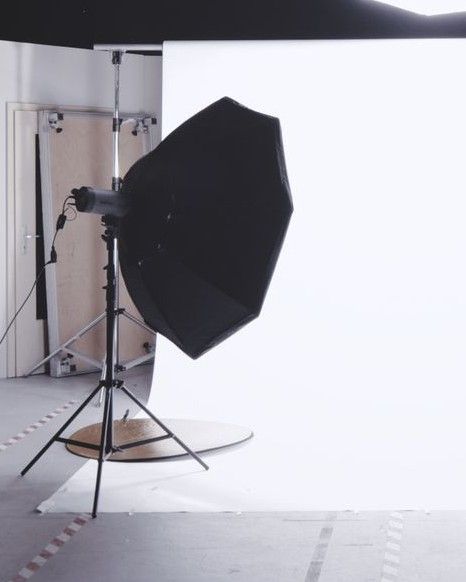 Photographe et son éclairage de studio installés dans une pièce lumineuse, séance sur site