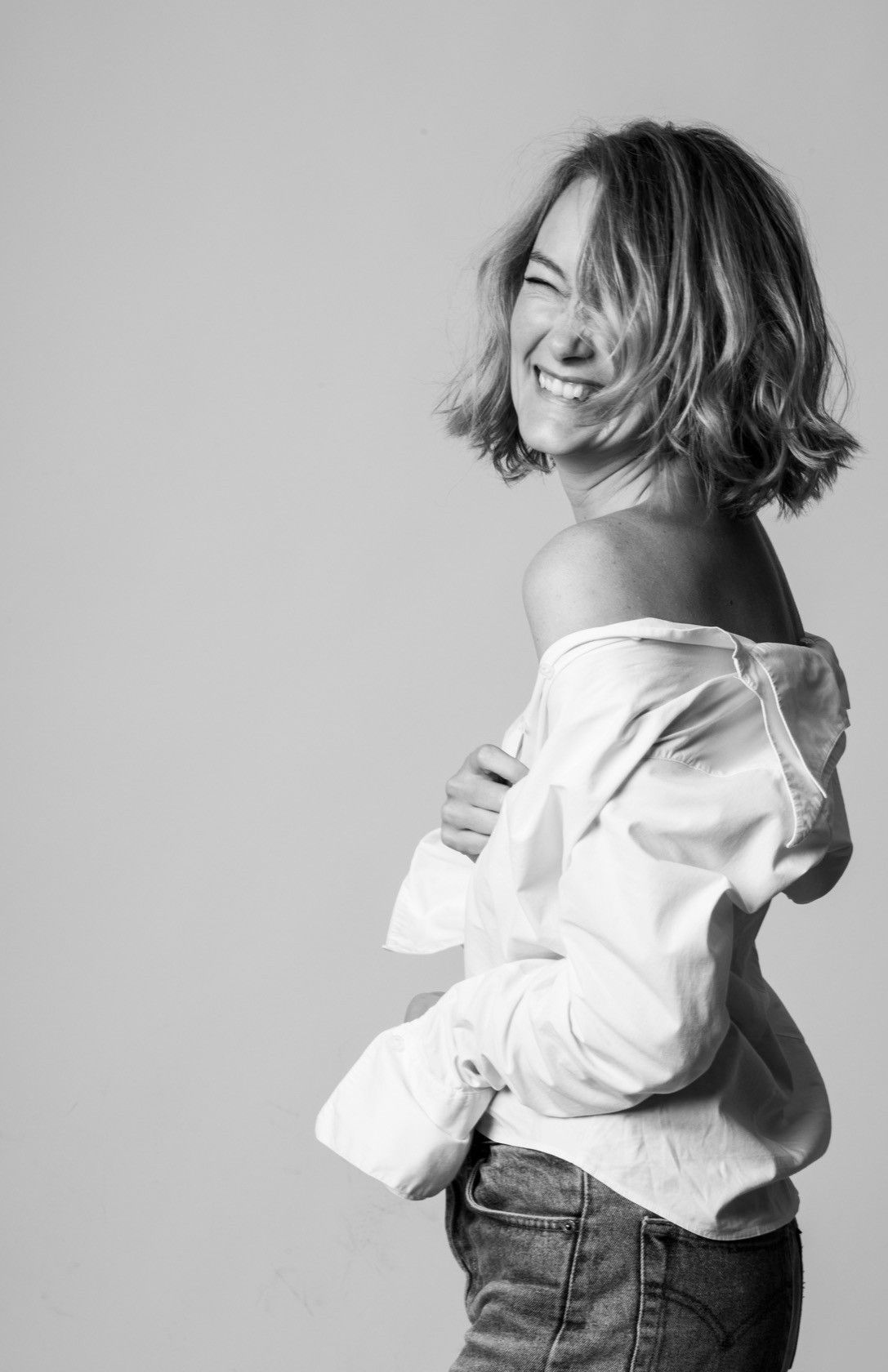 Woman laughing in a white shirt, spontaneous black and white portrait at the studio