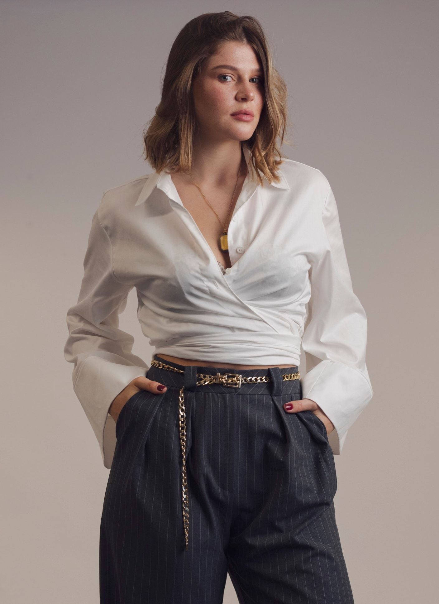 Woman in a white shirt and striped trousers, soft-toned colour portrait at the studio