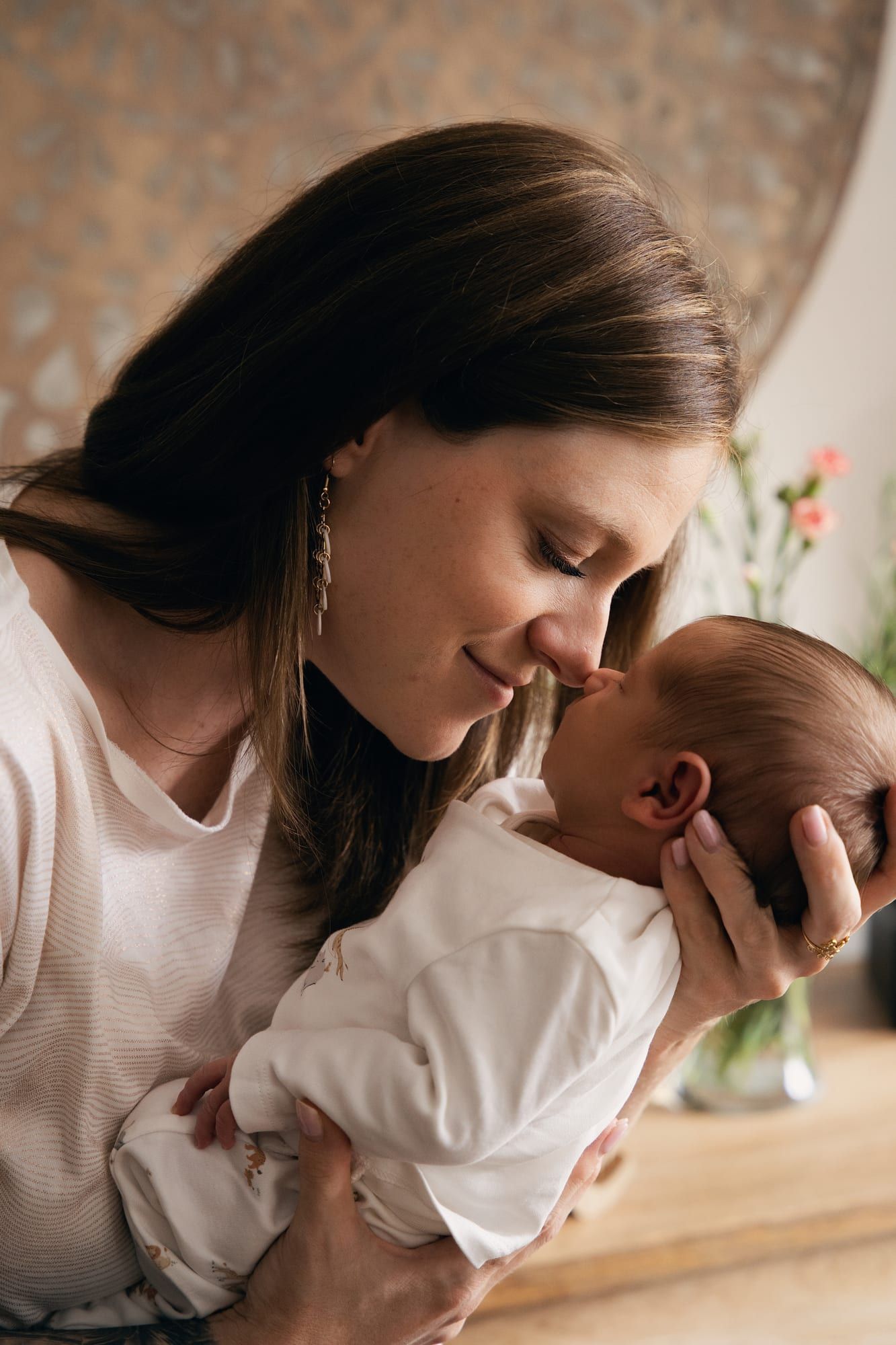 Mother holding her sleeping newborn against her, warm light in the studio (7)