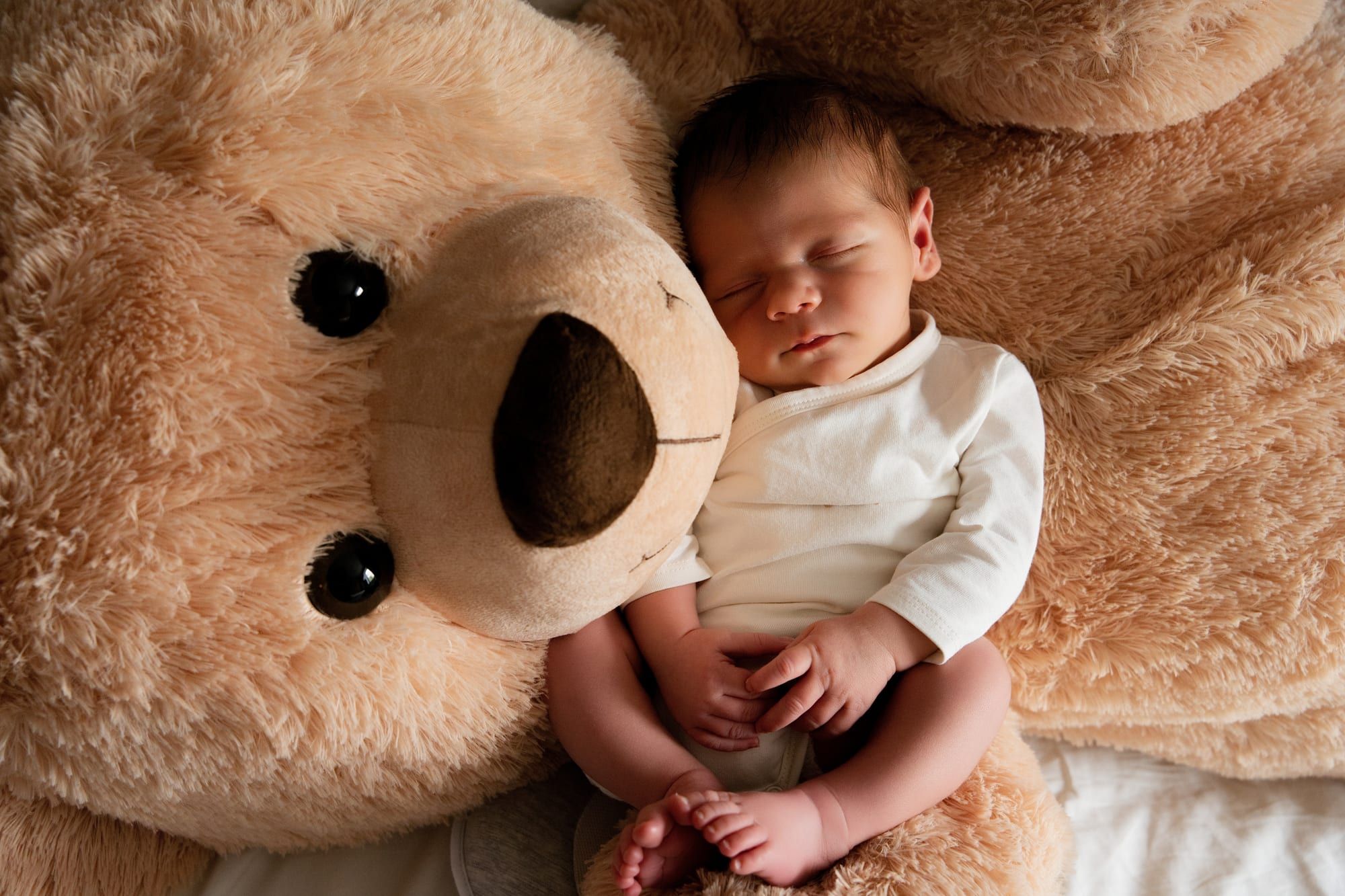 Mother holding her sleeping newborn against her, warm light in the studio (8)